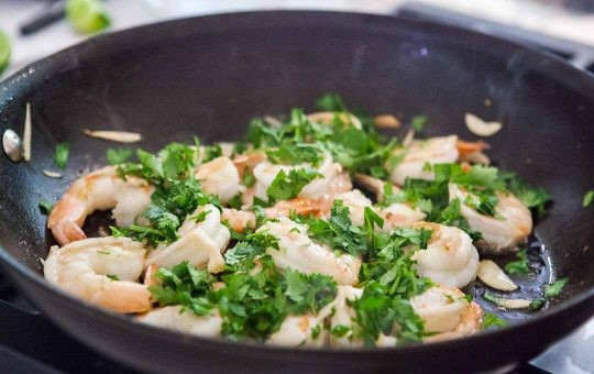 1. Этап. Креветки с чесноком и лаймом: 2. Почистите и нарежьте тонкими дольками чеснок, немного посолите. Добавьте чеснок в сковороду, готовьте 2-3 минуты, после выключите огонь. Промойте и измельчите кинзу. Посыпьте ею креветки.