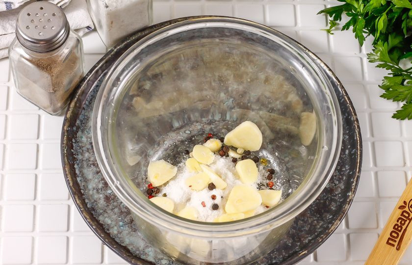 1. Этап. Пузанина в рассоле с чесноком: Очистите от шелухи зубчики чеснока и промойте в воде. Нарежьте слайсами и добавьте к соли.