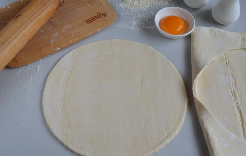 1. Этап. Слоеный пирог с семгой: Разложите тесто на столе, осторожно ножом вырежьте круг по диаметру формы так, чтобы получились небольшие бортики.