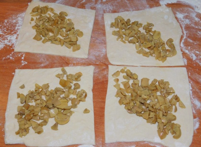 1. Этап. Грибные слойки с сыром: Выложите на каждый квадратик по диагонали мелко нарезанные грибы.