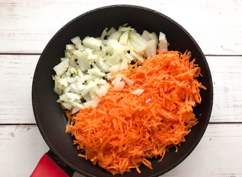 1. Этап. Рыба с рисом и овощами в духовке: Морковь хорошо помойте, почистите и натрите на средней терке. Лук очистите от шелухи и мелко нарежьте. Выложите овощи на хорошо разогретую сковороду с растительным маслом и обжарьте до золотистого цвета.