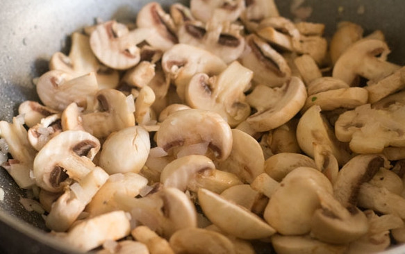 1. Этап. Грибы шампиньоны жареные: Разогрейте масло и обжарьте до золотистости лук с чесноком. Затем выложите грибы.