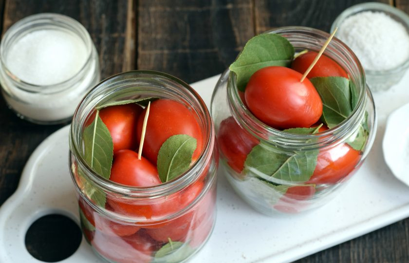 1. Этап. Помидоры с вишневыми листьями на зиму: Помидоры проткните в некоторых местах тонкой острой шпажкой. Эта манипуляция позволит не треснуть кожице в период заливки кипятком. Помидоры в целом виде выложите в банку как можно плотнее. Сверху и по бокам также выложите несколько листочков.