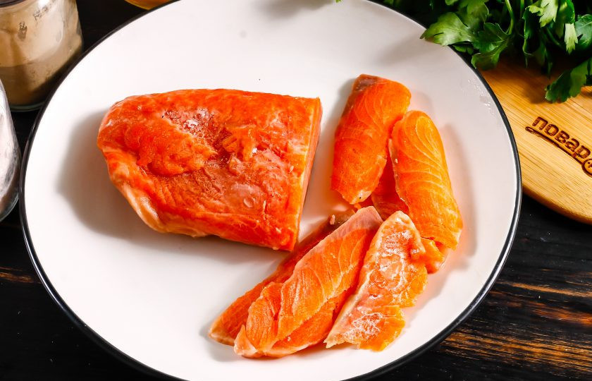 1. Этап. Строганина из рыбы: Кусочек замороженного лосося оставьте буквально на 5 минут при комнатной температуре, затем напилите острым ножом тонкие лепестки филе.