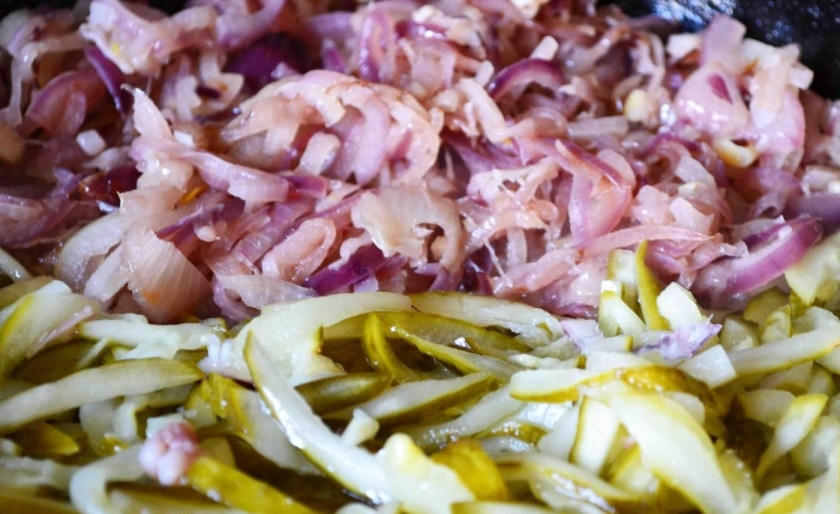 1. Этап. Солянка из рыбы: 3. Сковороду отправляю на огонь, вливаю в неё 2 ложки подсолнечного масла и обжариваю лук, затем добавляю к нему соленые огурцы и готовлю еще 5-7 минут.