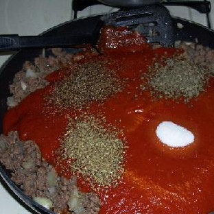 1. Этап. Тройной сырный Зити: После того, как мясо поджарится, сбавьте огонь. Смешайте соус с орегано, перцем, базиликом и сахаром. Выливаем соус на фарш.