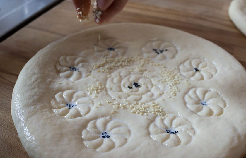 1. Этап. Лепешки из тандыра в духовке: Поверхность лепешки смазываем молоком, сверху украшаем кунжутом и седоной.