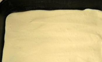 1. Этап. Заливной пирог с сайрой: Формы для выпечки необходимо смазать растительным маслом. Дно и бортики нужно присыпать манкой. Далее заливаем в форму половину теста, аккуратно разравниваем его при помощи ложки.