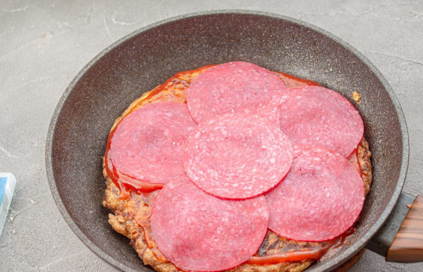 1. Этап. Пицца из кабачков без муки на сковороде: Выложите ломтики колбасы.