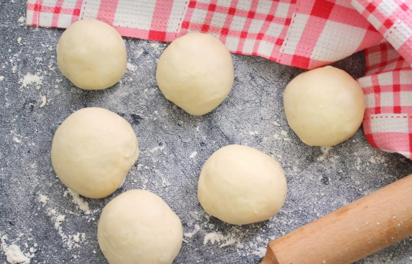 1. Этап. Пирожки с мясом и картошкой в духовке: Разделите тесто на одинаковые части и скатайте шарики. Накройте их и оставьте на 15-20 минут для расстойки.