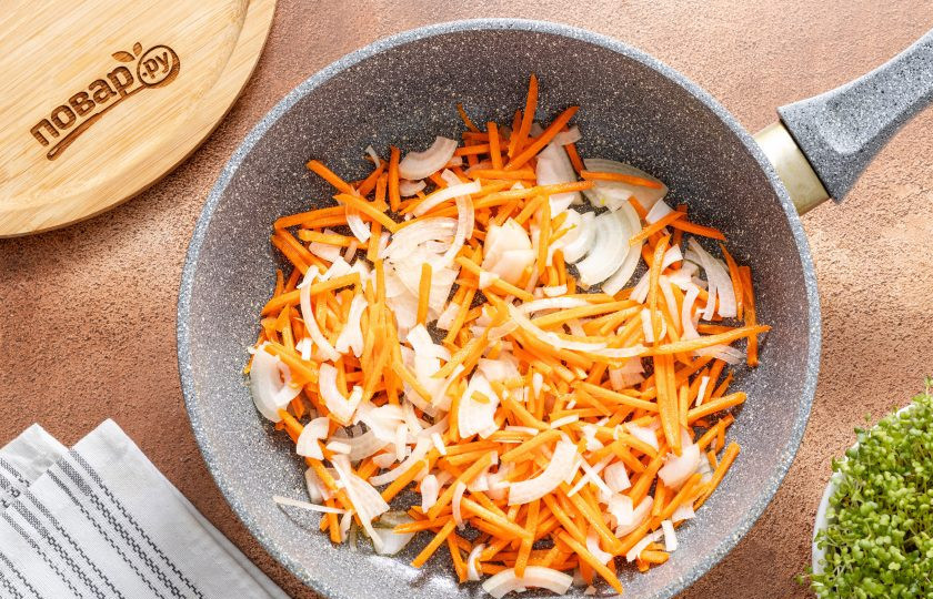 1. Этап. Тушеная капуста с соевым мясом: Репчатый лук нарежьте полукольцами, а морковь очистите и натрите на терке. Разогрейте сковороду с растительным маслом на среднем огне и выложите овощи.