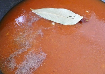 1. Этап. Рыбные тефтели: В это время готовим заправку для тефтелей. Вторую часть нашинкованного лука обжариваем до золотистого цвета. Затем вливаем в сковороду 1/2 стакана воды, добавляем томатную пасту, сахар, лимонный сок, солим и перчим. Кладем лавровый лист. Все хорошо перемешиваем и доводим до кипения. Кипятим 2 минуты.