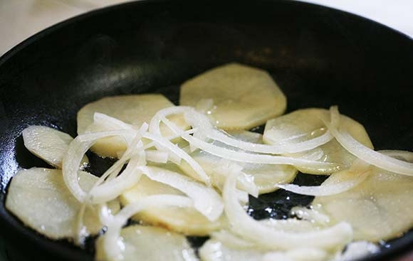 1. Этап. Домашняя жареная картошка с луком: 1. Картофель очистите от кожуры и нарежьте тонкими кружочками. Очистите лук от шелухи, затем нарежьте его тонкими кольцами. Сковороду отправьте на огонь, разогрейте с растительным маслом. Выложите картофель в один слой, затем добавьте лук.