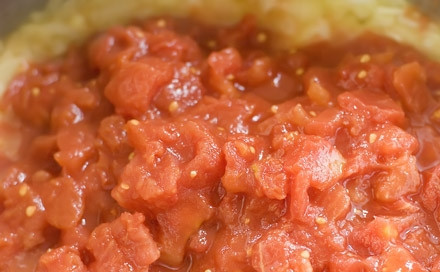 1. Этап. Суп с консервированными помидорами: Добавьте к луку мелко нарезанные консервированные помидоры.