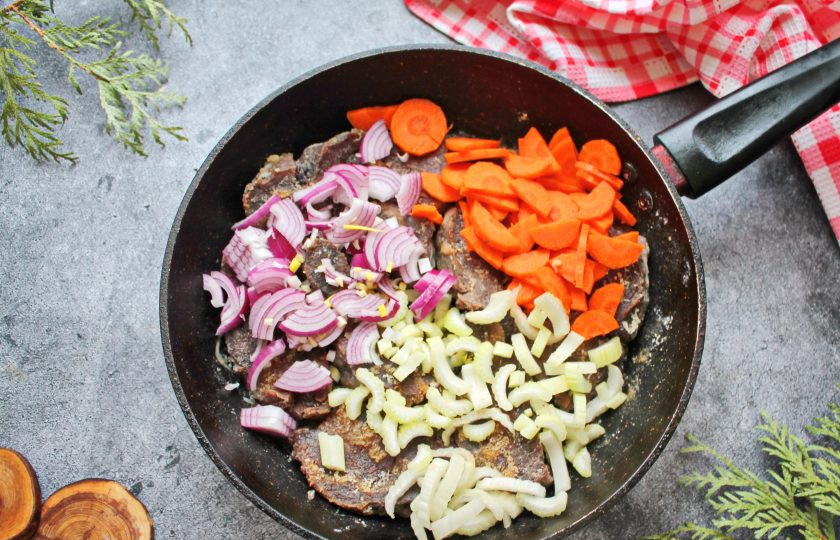 1. Этап. Томленые говяжьи щечки: В сковороду к щечкам добавляем нарезанный репчатый лук, морковь полукольцами и сельдерей, порезанный поперек соломкой. Обжаривайте все в течение 5 минут, перемешивая.