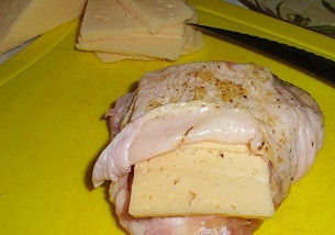 1. Этап. Куриные бедра в духовке с сыром: Сыр нарезаем пластинками по числу кусков курицы. Аккуратно ножом подрезаем кожу у каждого кусочка курицы и подсовываем под нее кусочки сыра