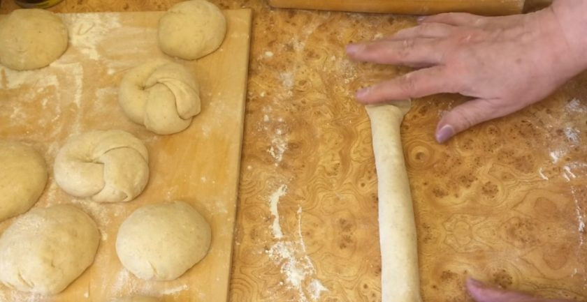 1. Этап. Булочки к чаю сдобные: 5. Раскатайте каждый шарик в тонкий круглый пласт, выложите вдоль края сахарный песок полоской, сверните в рулет и закрепите края с двух сторон.