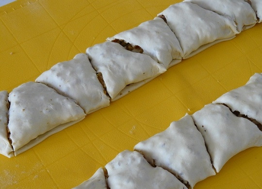 1. Этап. Рулет из сухофруктов и орехов: 6. Сделайте небольшие надрезы (можно обойтись и без этого, но в таком случае рулет из сухофруктов и орехов в домашних условиях можно будет сразу подавать к столу порционными кусочками). Выложите на пергамент и смажьте взбитым желтком. Отправьте в разогретую до 180 градусов духовку минут на 20-25.