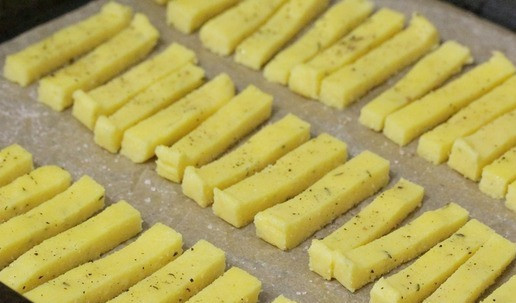 1. Этап. Полента а-ля картофель фри: Затем поленту нарезать на тонкие ломтики размером с картофель фри. Выложить ломтики на противень, застеленный бумагой для выпечки. Смазать ломтики маслом, посолить, поперчить. Поставить в духовку, разогретую до 180 °С, и запекать минут 25-30. При необходимости можно перевернуть ломтики в середине запекания.