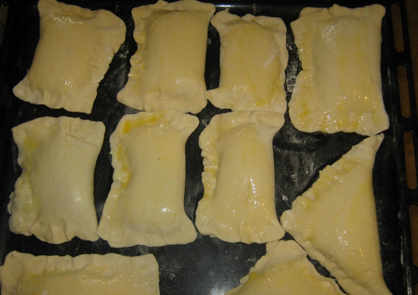 1. Этап. Слойки с творогом и изюмом: 9. Противень посыпаю мукой и выкладываю на него пирожки, смазываю их яйцом для румяной корочки.