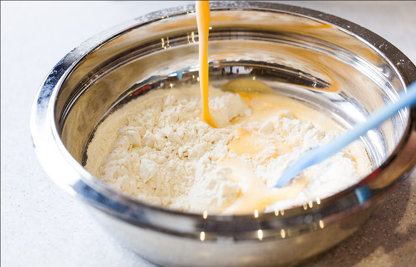 1. Этап. Чак-чак без водки: Добавляем чуть больше половины муки и перемешиваем. Комочков не должно быть.