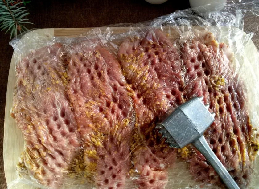 1. Этап. Мясо по-французски на Новый год: Накройте мясо пищевой пленкой и отбейте молоточком так, чтобы мясо не порвалось. Оставьте мариноваться на 15 минут.