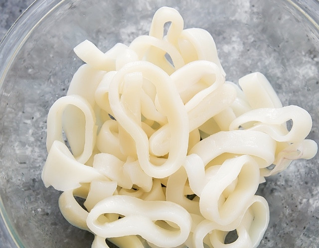 1. Этап. Кальмар в духовке: Поставьте духовку разогреваться до 200 градусов. Возьмите противень (или сразу 2) и застелите бумагой для выпечки. Кальмара, если он у вас заморожен, разморозьте, очистите и нарежьте кольцами. Я купил уже нарезанные кольца кальмара.