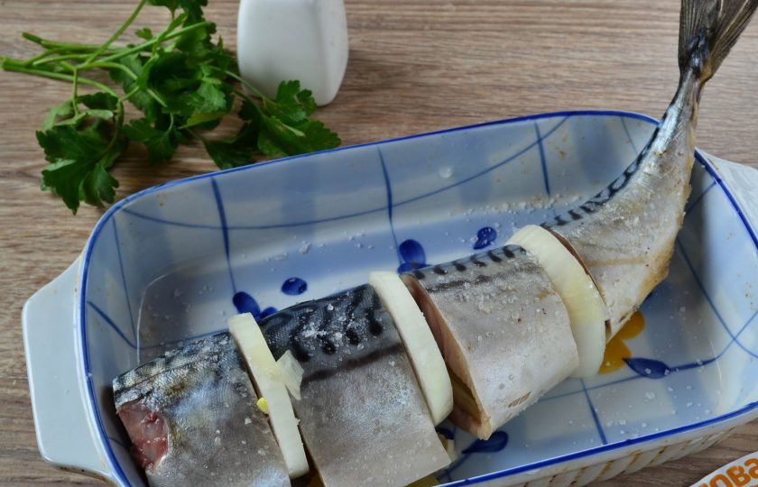 1. Этап. Запеченная скумбрия с луком и лимоном: 5. Кусочки скумбрии посолите внутри и снаружи. Внутрь положите по 1 ломтику лимона. Кусочки переложите в форму для запекания и переложите их кружочками лука.