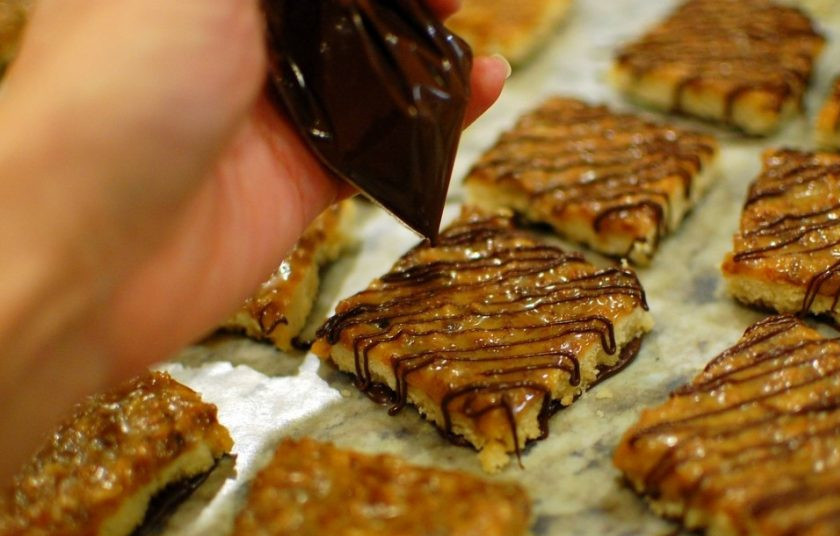 1. Этап. Пирог с ирисками и кокосом: 11. Остатки шоколада сложите в пакет и сделайте маленькую дырочку в углу, через нее украсьте кусочки сверху и оставьте их до застывания.