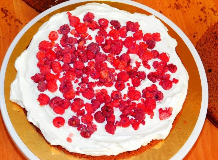 1. Этап. Шоколадный торт с малиной: Каждый корж немного пропитайте водой. Смажьте кремом и выложите ягоды малины. Обмажьте верх и бока торта кремом.