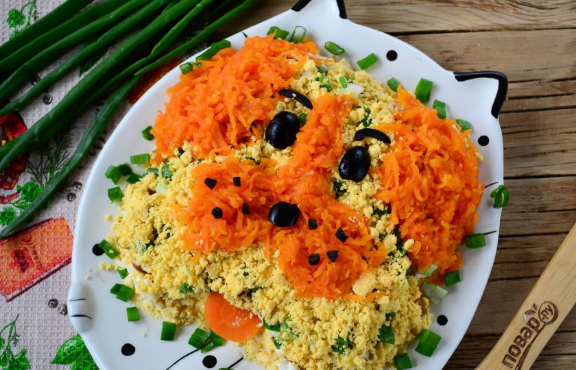 1. Этап. Салат Желтая собака: И последний штрих - декор. Желтки растолките в крошку, морковь натрите на мелкой терке. Из моркови сделайте уши и нос, все остальное пространство заполните желтком. С помощью маслин сделайте глазки и носик.