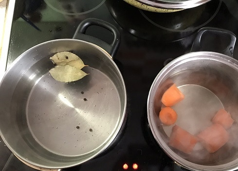 1. Этап. Рыбный салат Раковые шейки: Первым делом ставим на плиту две кастрюли с водой. В первую кладем лавровый лист и черный перец горошком. Во вторую - мытую, очищенную и порезанную морковь.