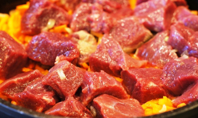 1. Этап. Плов из говядины: Мясо промойте, нарежьте кубиками и добавьте в сотейник.