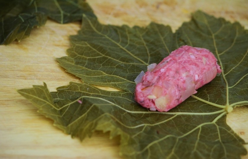 1. Этап. Долма по-азербайджански: 7. Лист положите на стол или донышко блестящей стороной вниз, срежьте толстую ножку, если таковая имеется. В центр выложите добрую ложку начинки.