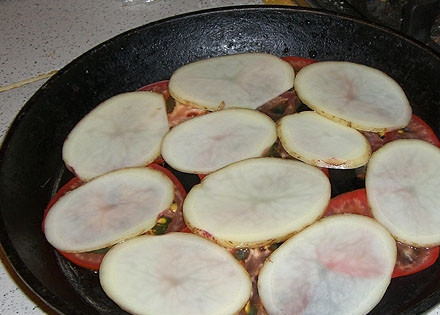 1. Этап. Сулугуни, жаренный на кеци: Промойте картофель. Тонко нарежьте его кружками. Выложите на помидор.