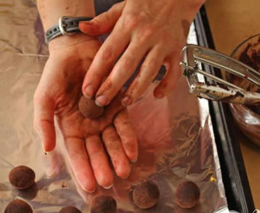 1. Этап. Трюфели-божьи коровки: 3. Выстелить противень фольгой или пергаментной бумагой. Достать шоколадную смесь. Руки смазать какао порошком, чтобы шоколад не лип. При помощи ложки сформировать 24 небольших шарика. Из остатков шоколадной смеси сформируйте 24 шарика меньшего размера. Это будет голова божьей коровки. Растопить шоколадную глазурь и склеить два шарика разного размера между собой.