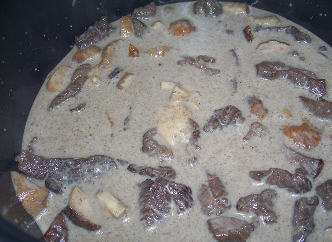 1. Этап. Бефстроганов из оленины: 6. Заливаем сметаной и накрываем крышкой. Тушим наше мясо с грибами около часа, периодически подливая воду. Если вам покажется, что оленина жестковата, убавьте огонь, долейте еще стакан воды и тушите еще около 40 минут.