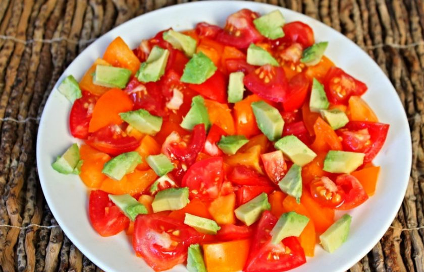 1. Этап. Салат из помидоров с авокадо, кукурузой и луком-пореем: Нарезанные кусочки авокадо вынимаем чайной ложкой и выкладнываем на помидоры.