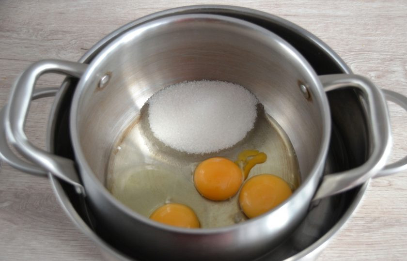 1. Этап. Лимонный пирог Нежный: Поставьте в кастрюлю с горячей водой еще одну кастрюлю, вбейте в нее 2 яйца и 1 желток, всыпьте сахар и размешайте до растворения сахара.