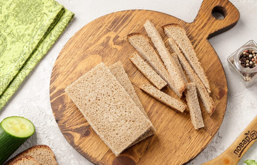 1. Этап. Канапе со шпротами и огурцом: Для начала срежьте у хлеба корочку со всех сторон. Если будете использовать тостовый хлеб или багет, то этот шаг можете пропустить.