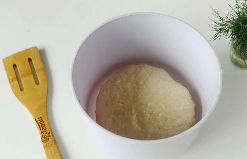 1. Этап. Чесночные пампушки на кефире: Замесите мягкое тесто, соберите его в шар, смажьте растительным маслом и накрыв миску полотенцем оставьте в тепле на 1,5 часа. Если тесто в процессе замешивания сильно липнет к рукам, то дополнительно можно добавить еще примерно 1-2 ст.л. муки.