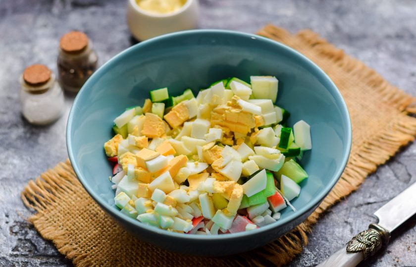 1. Этап. Салат с кукурузой, авокадо и крабовыми палочками: Куриное яйцо отварите вкрутую, после очистите и нарежьте яйцо кубиками, добавьте в салат.