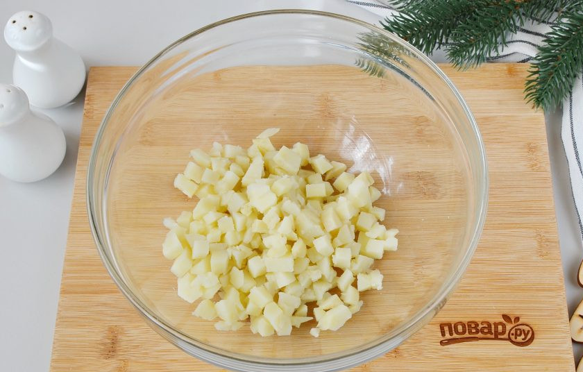 1. Этап. Салат Тигр в шубе на Новый год: Очищенный картофель порежьте кубиками. Выложите в большой салатник.