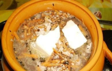 1. Этап. Гречка в горшочках: По истечении времени аккуратно извлекаем горшочек из духовки и выкладываем в него предварительно промытую гречку. Доливаем еще пол стакана кипятка (так чтобы жидкость была на 1-1,5 сантиметра ниже края), солим, аккуратно перемешиваем и сверху добавляем кусочек масла. Теперь его можно возвращать в духовку, закрыв крышкой. Готовим еще пол часа, а когда время выйдет, выключаем огонь и 20 минут даем постоять горшочку в духовке.