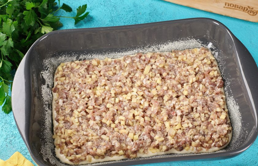 1. Этап. Заливной пирог на кефире и майонезе: Форму для выпечки смажьте маслом. Дно и бока присыпьте мукой или манкой. Налейте примерно половину порции теста и выложите равномерно начинку.