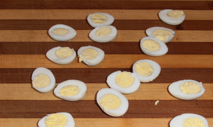 1. Этап. Новогодний салат из кальмаров: Сваренные яйца очищаем, разрезаем пополам.