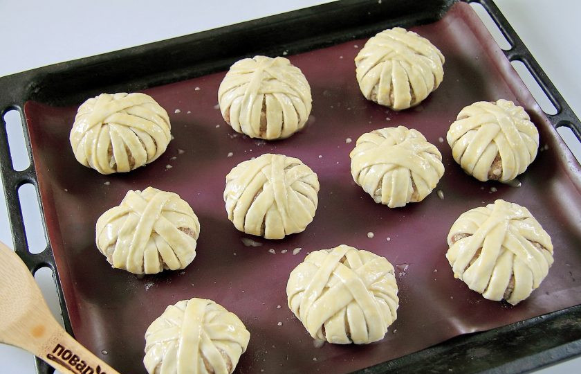 1. Этап. Мясные шарики в слоеном тесте: Переложите мясные шарики на противень, застеленный пергаментом или силиконовым ковриком. Смажьте смесью из желтка и молока для придания им румяного цвета и готовьте при температуре 180 градусов около 40 минут.