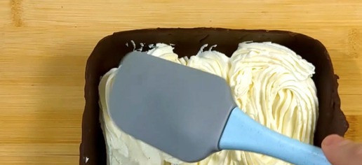 1. Этап. Шоколадный десерт с нежным творожным кремом: Подготовка крема. Добавьте 50 г сливочного масла, 150 г сахарной пудры и 220 г творожного сыра в чашку и взбейте всё вместе миксером. Крем готов! Переверните шоколадную форму и выложите на дно половину крема выровняв лопаткой.