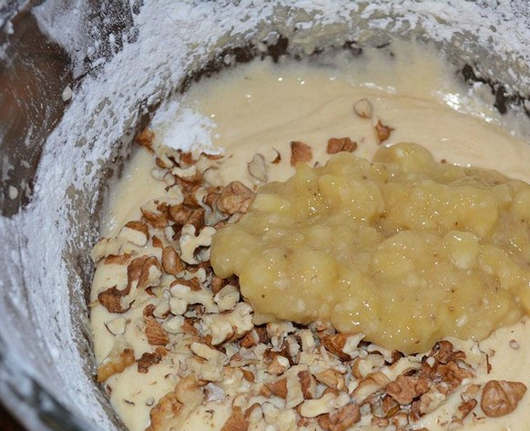 1. Этап. Постная банановая коврижка в мультиварке: Просеиваем муку. Смешиваем ее с разрыхлителем, ванилином, щепоткой соли и сахаром. Соединяем подсолнечное масло с газированной водой, смешиваем с мукой, тщательно растирая комочки вилкой. В конце добавляем банановое пюре и орехи. Замешиваем тесто.