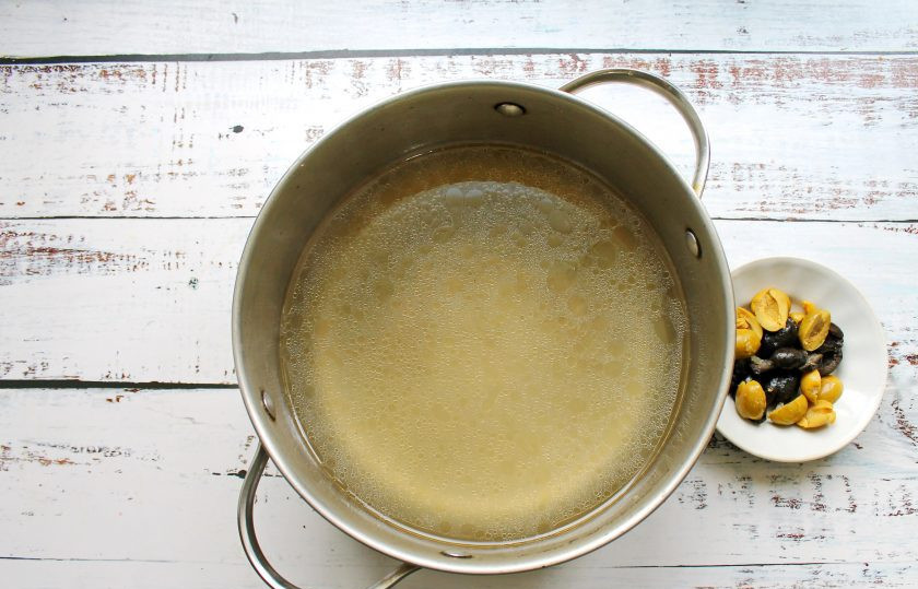 1. Этап. Солянка с жидким дымом: Кости вымойте, выложите в кастрюлю и залейте холодной водой. Поставьте кастрюлю на средний огонь и доведите до кипения. Посолите, добавьте луковицу и очищенную морковь. Варите, снимая пену в течение одного часа на медленном огне. Бульон процедите, выложите в него нарезанные маслины и оливки. Срежьте с костей мясо и добавьте в бульон.